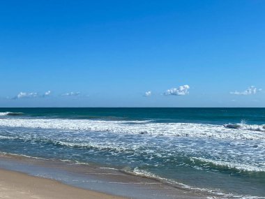 Dalgaların kuma vurduğu manzaralı bir sahil manzarası.