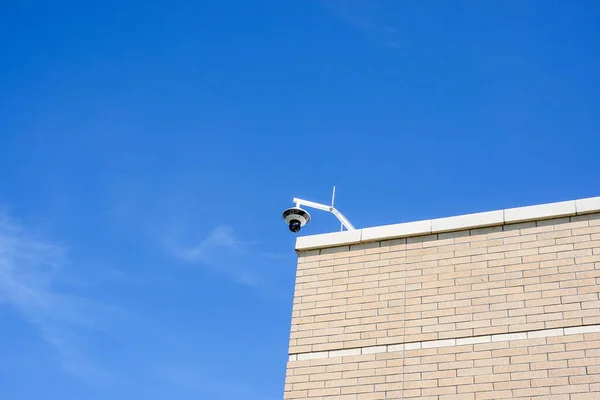 A security camera on a building overlooking a sidewalk with copy space.