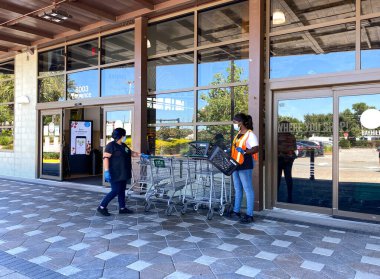 Orlando, FL / USA-5 / 3 / 20: Whole Foods marketinin önünde market sepetleri ve arabaları sterilize eden çalışanlar.
