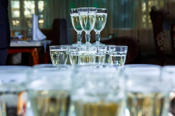 a tower of several dozen glasses with champagne in a restaurant