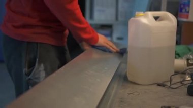 İşçi eli, metal ürünü bir bez parçasıyla siliyor.