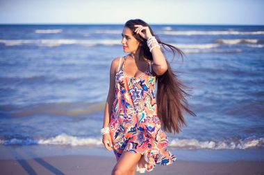 Güzel esmer kız bir sahil üzerinde poz. Şık takı. 