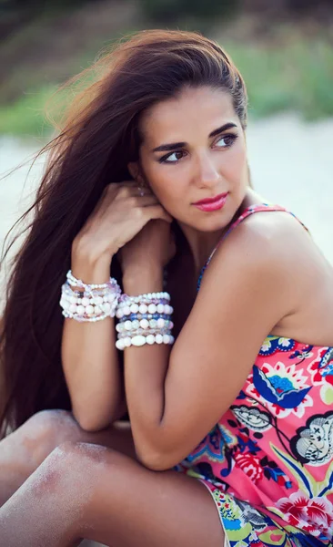 Güzel esmer kız bir sahil üzerinde poz. Şık takı. 