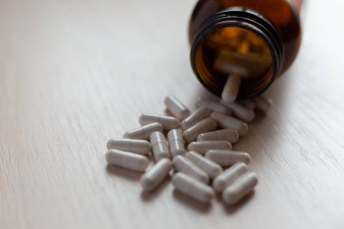 İlaç şişesinden beyaz ilaç ve haplar dökülüyor.