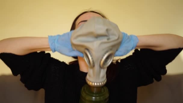 Witte vrouw in medische handschoenen zet op een gasmasker — Stockvideo