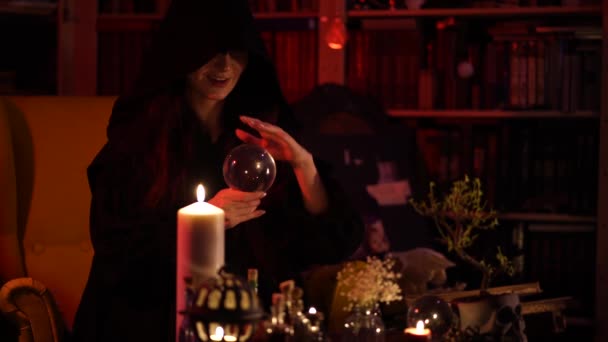 Chica en túnica negra adivina en una bola de cristal — Vídeos de Stock