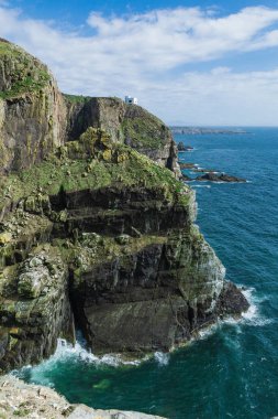 Sahilin kayalıklardan ve beyaz bir evden oluşan dramatik manzarası. Holyhead Yarımadası, Galler, Uk yazın mavi deniz ve gökyüzü.