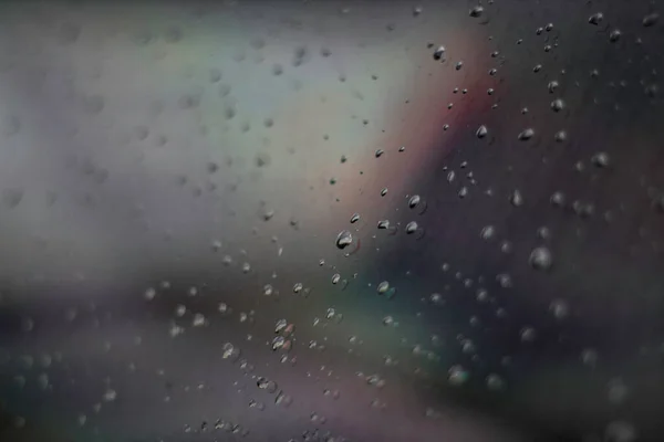 Raindrops on car glass with colorful background