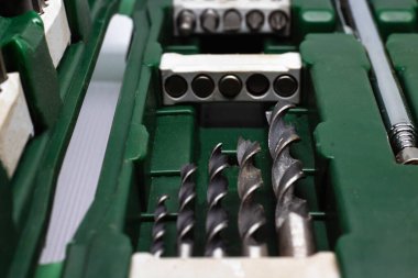 Matkaplı bir tornavida ve yakın çekim tornavidaları için bir set hortum. Koyu yeşil bir tornavida. Gri matkaplar