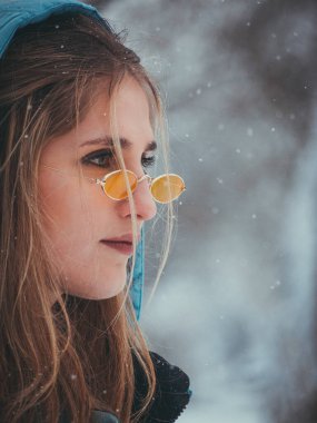 Sarı saçlı, mavi ceketli ve gözlüklü genç bir kızın portresi.