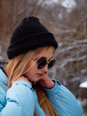 Sarı saçlı, mavi ceketli ve gözlüklü genç bir kızın portresi.