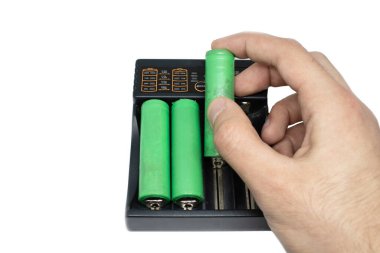 El, tip 18650 pili beyaz arka planda izole edilmiş şarja koyar.