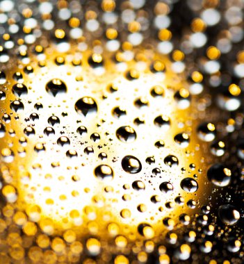 Su damlaları, saydam sarı arkaplanda yağmur.