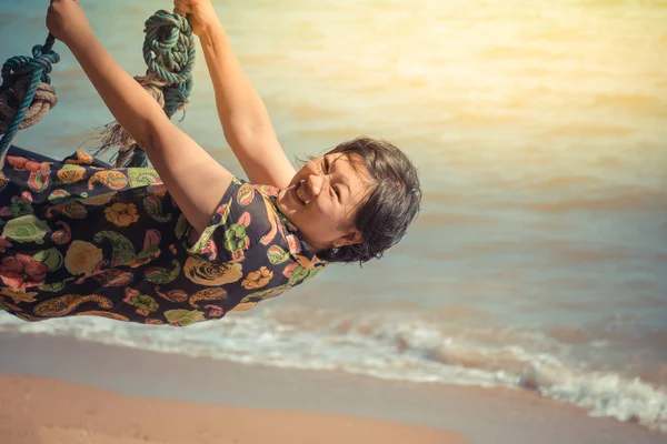 Asia donna in posa su altalena in spiaggia con mare blu e cielo — Foto Stock