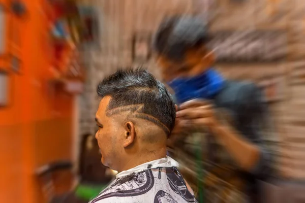Barbeiro corte de cabelo de um cliente na barbearia — Fotografia de Stock