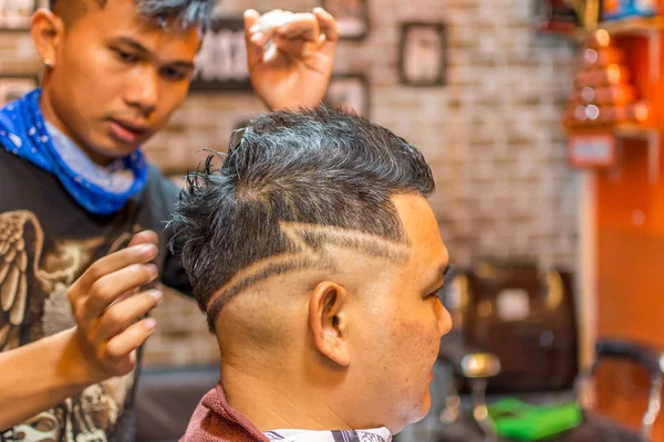 Barbeiro corte de cabelo de um cliente na barbearia — Fotografia de Stock