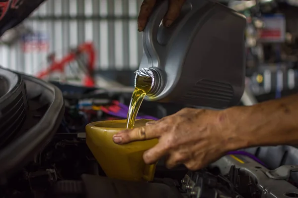 Mecânico de carro enche um óleo de motor lubrificante fresco — Fotografia de Stock