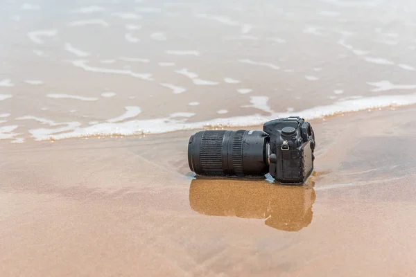 Camera on a beach it wet from sea wave — Stock Photo, Image