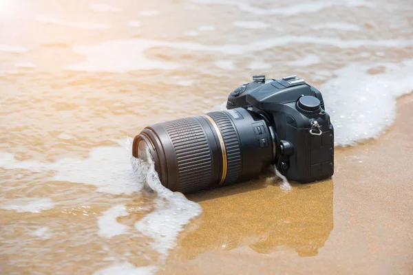 Camera on a beach it wet from sea wave — Stock Photo, Image