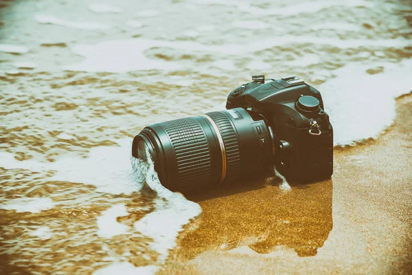 Φωτογραφική μηχανή σε μια παραλία, αυτό υγρός από το κύμα της θάλασσας — Φωτογραφία Αρχείου