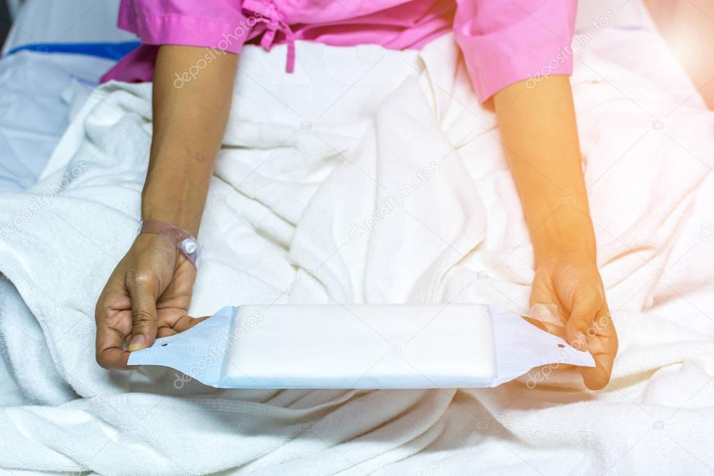 Patient woman using sanitary napkin on bed