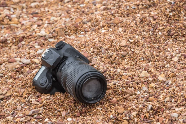 Câmera DSLR na praia de pedra molhada da onda do mar da água — Fotografia de Stock
