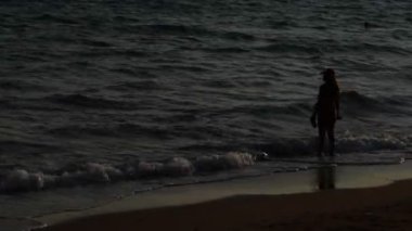 Kumsalda yürüyen kadın silüeti