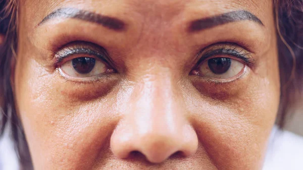 Asian elder women show her eyes and eyebrow tattoo