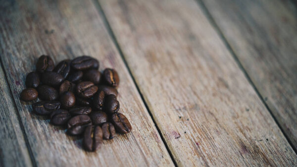 Coffee beans and roasted coffee beans on wooden table in a cafe or coffee shop, traditional vintage style concept