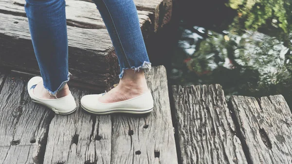 Ноги женщины одеваются в синие джинсы и белые туфли — стоковое фото