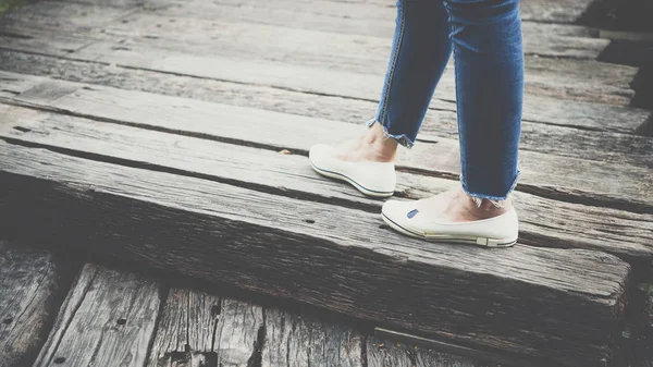 Ноги женщины одеваются в синие джинсы и белые туфли — стоковое фото