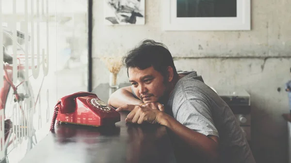 Asian man shy waiting phone call in a coffee shop