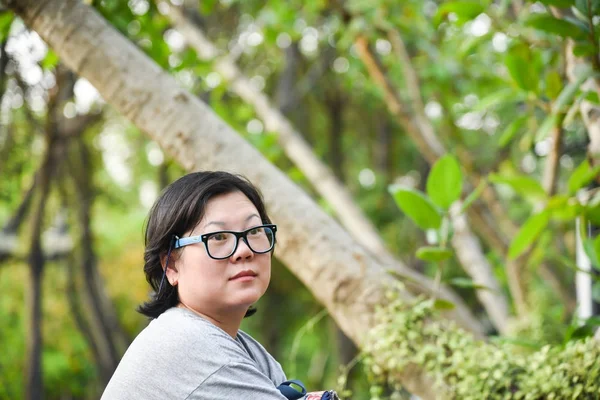 Mujer asiática con gafas sentado para relajarse en el parque — Foto de Stock