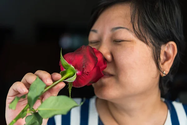 Mujer oliendo flor de rosa roja en San Valentín — Foto de Stock
