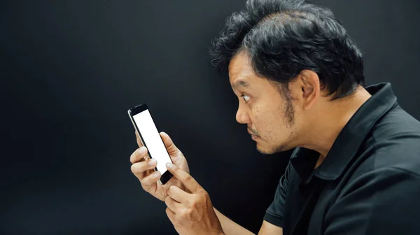 Азиатский мужчина оглушен использованием смартфона в темном стиле — стоковое фото