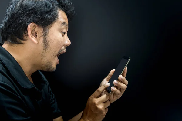 Asian Mężczyzna oszołomiony, przy użyciu smartfona w mrocznym klimacie — Zdjęcie stockowe