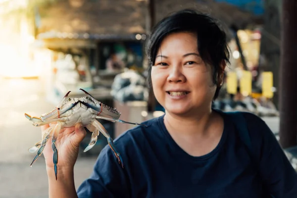 Mujer asiática y cangrejo de flores en el mercado de mariscos tailandés — Foto de Stock