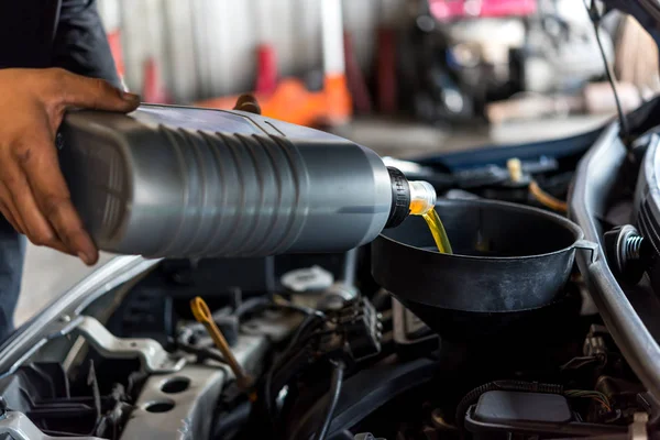 Автомеханик наполняет масло свежего смазочного двигателя — стоковое фото