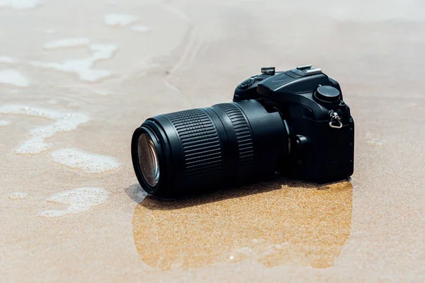 DSLR camera on beach wet from water sea wave — Stock Photo, Image