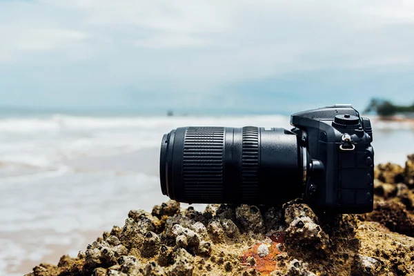 DSLR camera on stone beach wet from water sea wave — Stock Photo, Image