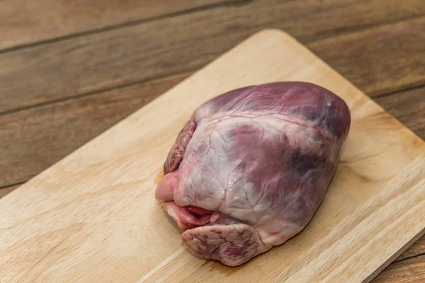 Fresh pig heart on wooden cutting board