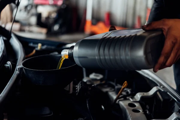 Mecánico de coche llena un lubricante fresco aceite de motor — Foto de Stock