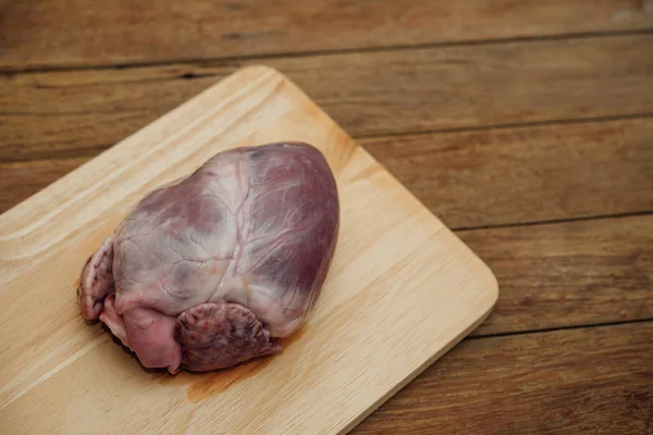 Fresh pig heart on wooden cutting board