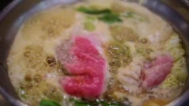 쇠고기 돼지고기 야채를 뜨거운 남비에 요리하여 식당에서 수키야 만든다 — 비디오