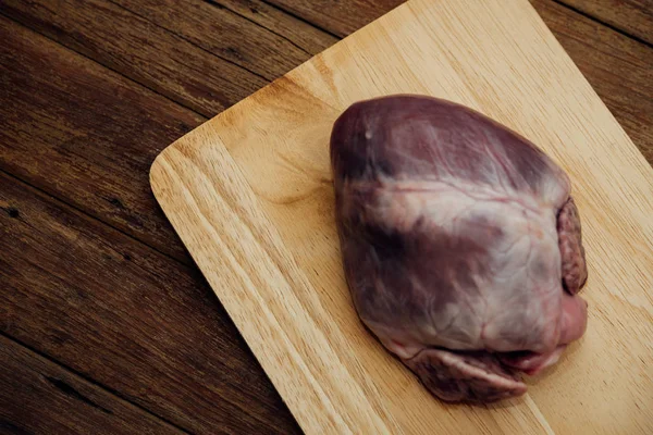 Fresh pig heart on wooden cutting board