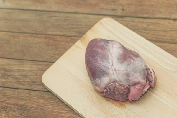 Fresh pig heart on wooden cutting board