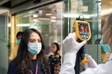 Asyalılar, Wuhan 'ın ofisinden gelen salgın gribe karşı vücut ısısını ölçmeyi bekliyor.