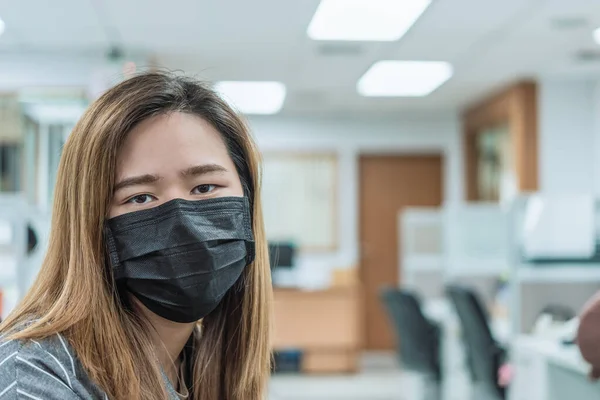 Asian pretty woman wearing mask respiratory protection mask against epidemic flu covid19 or corona virus from wuhan in office with fear emotion in concept illness, outbreak, healthcare in life