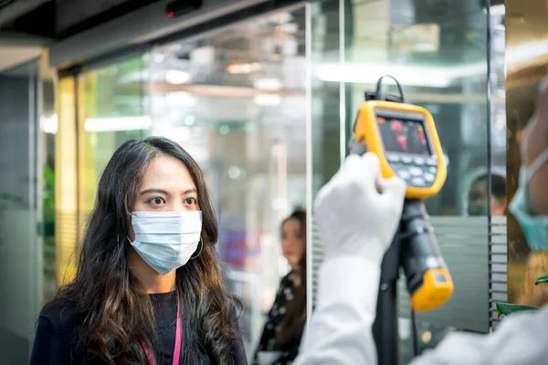 Asian people waiting for body temperature check before access to building for against epidemic flu covid19 or corona virus from wuhan in office by thermoscan or infrared thermal camera