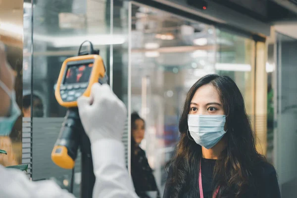 Asian people waiting for body temperature check before access to building for against epidemic flu covid19 or corona virus from wuhan in office by thermoscan or infrared thermal camera